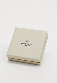 Štvorcová, textúrovaná, svetlo béžová krabica s jemným vzorom listov a čiernym logom "PURELEI" umiestneným v strede vrchu.