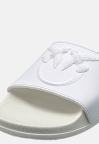 Sandalo bianco con design a rilievo di un uccello sulla fascia, suola testurizzata e finitura liscia. Nessun ulteriore abbellimento o colore presente.