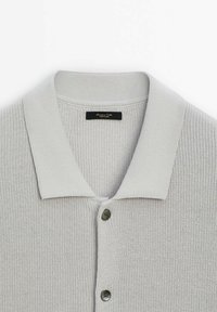 Cardigan en maille gris clair avec un col côtelé et deux boutons sombres visibles à l'avant.