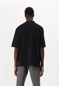 Sort kortærmet t-shirt i blød bomuld med en afslappet pasform, der har detalje med subtilt logo på bagsiden nær sømmen.