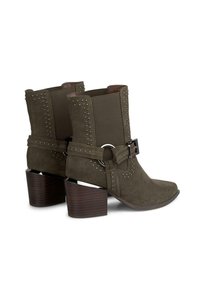Zielone zamszowe botki za kostkę z szpiczastymi noskami, ozdobione srebrnymi nitami, szerokim paskiem z okrągłą klamrą oraz masywnymi drewnianymi obcasami.