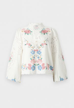 Λευκό μπλουζάκι με μακριά μανίκια, λεπτομέρειες από δαντέλα και πολύχρωμη κεντητή λουλουδένια διακόσμηση σε ροζ, μπλε και πράσινο, με ψηλό γιακά από δαντέλα και κουμπιά μπροστά.