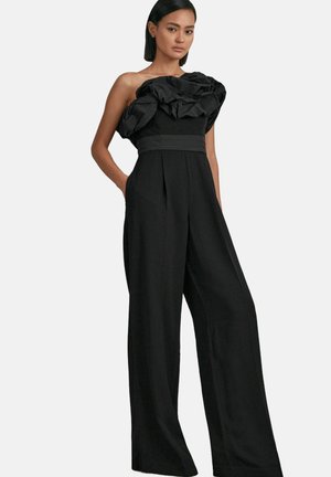 Sort jumpsuit med en volangdetalje uden skuldre, brede ben og en tætsiddende talje. Glat stof med en let glans.