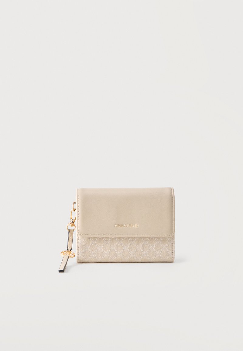Portefeuille compact beige avec moitié inférieure texturée, rabat lisse, logo doré "ANNA FIELD" et un porte-clés doré avec une sangle noire attachée.