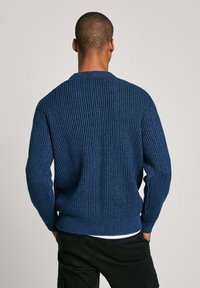 Maglione azzurro lavorato a maglia con texture a coste, scollo rotondo e maniche lunghe. La vestibilità è rilassata, con dettagli sottili ai polsini e all'orlo.