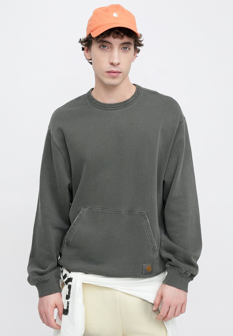 Grå sweatshirt med rund halsringning, långa ärmar och framficka; kombinerad med orange keps med logotyp; mjukt, avslappnat tyg.