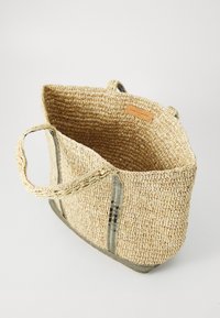 Woven straw tote bag with two handles, featuring green and brown stripes and a leather label. Open top, lightweight, and spacious interior.