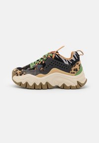 Baskets épaisses avec motifs animaliers, lacets verts, superpositions beige clair et noires, et semelle beige épaisse à crampons robustes.