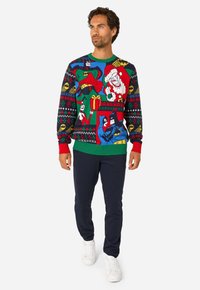 Värvikas kootud jõulutreening koomiliste tegelastega, punase, rohelise, sinise ja musta mustriga; sellega kaasas meresinine püksid ja valged kingad.