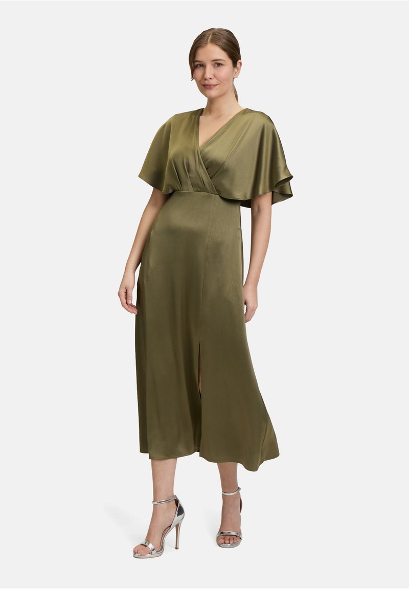 Satin in olivgrün, Wickelkleid mit kurzen Capärmeln, tiefem V-Ausschnitt und seitlichem Schlitz, kombiniert mit silbernen High-Heels.