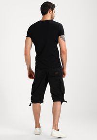 Black cotton T-shirt and black cargo shorts with pockets, paired with white sneakers. Cargo shorts include adjustable hems and textured fabric.