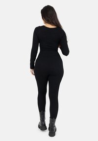 Zwarte ribgebreide bodysuit met lange mouwen, slank silhouet en ronde halslijn, gecombineerd met zwarte enkellaarsjes met chunky zolen.