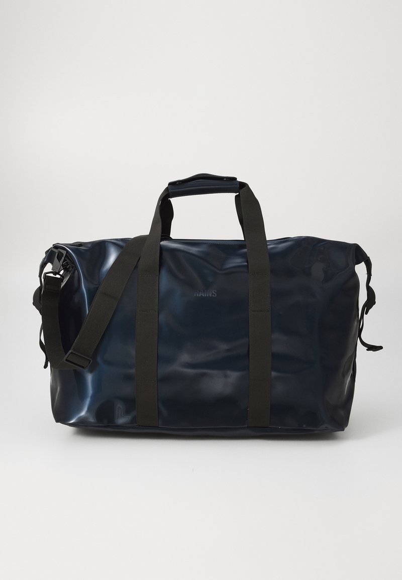 Borsa duffel blu marina con manici e cinturini neri, caratterizzata da una finitura lucida e un logo sul lato, su uno sfondo bianco semplice.