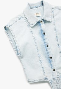 Chaleco de mezclilla azul claro con un cuello tipo camisa, cierre delantero de botones y mangas cortas. Ofrece una textura desgastada y un acabado limpio.