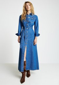 Jeans-Maxikleid mit durchgehender Knopfleiste, langen Ärmeln und tailliertem Gürtel. Der Stoff ist blau und leicht strukturiert.