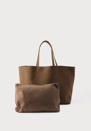 Bruine leren shopper met twee handvatten en een bijpassend bruin geperforeerd tasje dat ervoor op een witte achtergrond ligt.