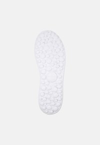 White rubber shoe sole featuring a textured pattern of circular bumps for traction and comfort. Rounded shape with a smooth finish.