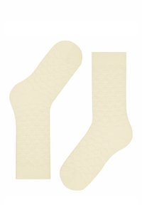 Chaussettes en coton couleur crème avec un motif ondulé texturé, dotées de bords côtelés et de bouts ronds. Matériau doux avec une finition lisse.