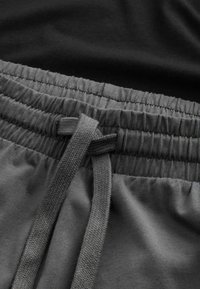Grijze sportshorts met een elastische tailleband en een trekkoord. De stof is soepel en flexibel, met subtiele textuur en stikseldetails.