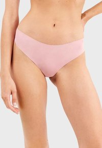 Bikini de culotte rosa sin costuras con una cintura ondulada y textura suave, que presenta un corte bajo y un diseño de cobertura mínima.