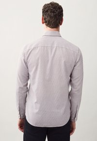 Gestreiftes Hemd in Weiß und Dunkelrot. Lange Ärmel, Knopfmanschetten, Standardkragen und gerader Saum. Rückansicht zeigt das Design.