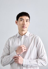 Camisa de botones a rayas hecha de una tela ligera, con rayas verticales de colores múltiples, un cuello clásico y un diseño ajustado.