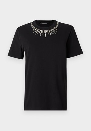 Črna bombažna majica s kratkimi rokavi, okrašena z ovratnikom iz okrasnih kristalčkov v vzorcu izbruha. Lahka in oprijeta zasnova.