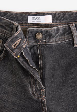 Sötét szürke denim, laza szabású, alacsonyan ülepelt farmernadrág, kontrasztos narancssárga varrással, fémből készült gombbal és cipzárral, belső címkével.