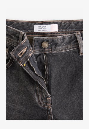 Pööräkkä alhaalla istuvat farkut tummanharmaasta denimmistä, joissa on erottuva oranssi ompelu, metallinen nappi ja vetoketjukiinnitys, sekä sisällä oleva etiketti.