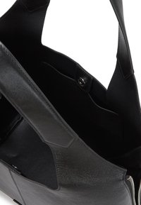 Sac fourre-tout en cuir noir avec un design structuré, extérieur lisse, poche intérieure et fermeture à bouton-pression. Fini texturé.