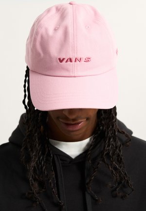 Cappello di cotone rosa con ricamo del logo "VANS" in rosa scuro. Presenta una visiera curva e fori di ventilazione. Indossato con un felpa nera.