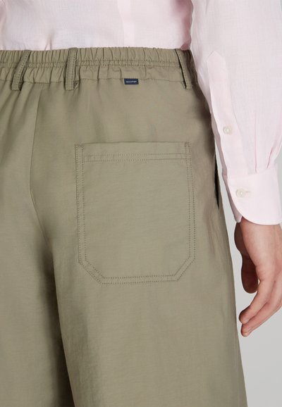 Jasnooliwkowe spodnie o luźnym kroju z elastycznym paskiem w talii, z kwadratową kieszenią i delikatnymi detalami w szwie.