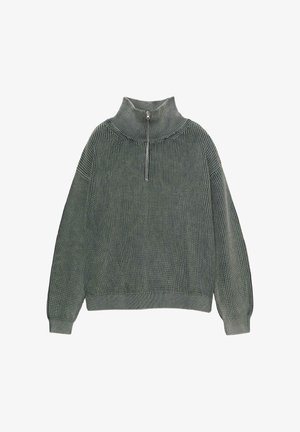 Maglione verde a coste con colletto alto e chiusura a mezza zip. Caratterizzato da maniche lunghe e una vestibilità rilassata. Texture morbida e design a maglia.