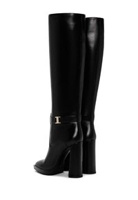 Černé kožené kozačky po kolena s blokovým podpatkem, se zlatým kováním a hladkým povrchem. Lehce zaoblený design špičky.