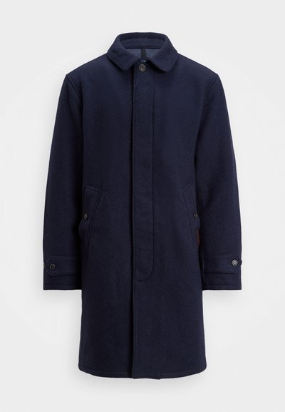 Jūras spēku zilas vilnas mētelis ar pogājamām priekšējām daļām, pīķa apkakli, divām sānu kabatām un pogājamām aprocēm. Gluda tekstūra ar niansētu rakstu detaļām.