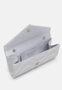 Prostokątny srebrny kopertówka z teksturowanym falistym wzorem, otwieraną klapką, gładkim satynowym wnętrzem, wewnętrzną kieszenią i zapięciem na magnes.