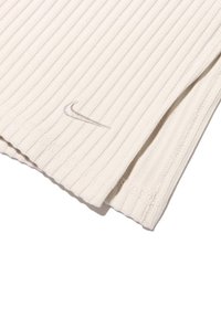 Maglietta beige a coste Nike con logo ricamato, caratterizzata da righe verticali e orli cuciti, realizzata in materiale leggero e testurizzato.