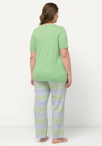 Top de algodón verde de manga corta combinado con pantalones de pijama con un diseño de olas en tonos pastel de azul y verde. Corte suave y relajado.