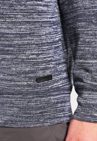 Maglione a maglia tessurizzata in blu navy e grigio con un sottile motivo a righe. Presenta un'etichetta nera sull'orlo e polsini a costine per aggiungere texture.