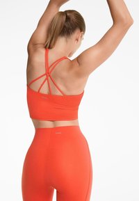 Piros sportos cropped top keresztpántokkal és hozzáillő magas derekú leggings, sima, rugalmas anyagból készült. OYSHO logó látható.
