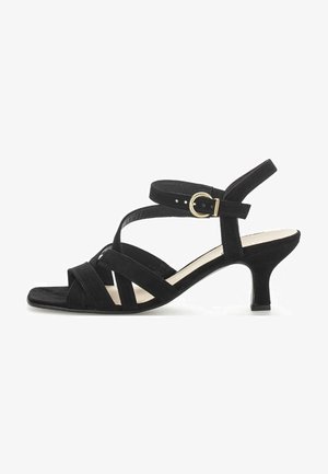 Sandale en suede noire avec des brides entrecroisées, bout ouvert et petit talon. Comprend une fermeture à boucle avec des accents dorés.
