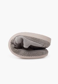 Gray fabric slip-on shoe with a textured woven upper, flexible sole, and padded interior. Rounded shape with a low profile design.