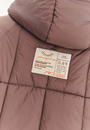 Kurtka pikowana w stonowanym fiołkowym kolorze, z przeszywanym wzorem. Zawiera kremową metkę z pomarańczowym napisem, zawierającą instrukcje pielęgnacji i branding.