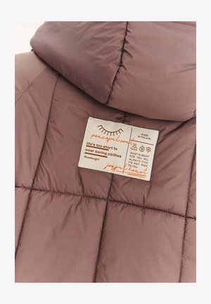 Preštepovaná bunda v tlmenej fialovej farbe s prešívaným vzorom. Obsahuje krémovú štítok s oranžovým textom, ktorý obsahuje pokyny na starostlivosť a branding.