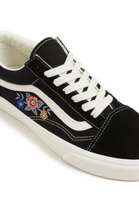 Schwarze Low-Top-Sneakers mit weißen Schnürsenkeln und Sohle, weißem Seitenstreifen und gestickten Blumenmotiven in Blau, Pink und Orange.
