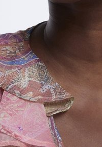 Blusa in broccato con un motivo floreale rosa e multicolore, presenta un ampio colletto e una texture morbida e trasparente.
