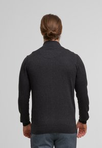 Dark gray knitted sweater with long sleeves, a high collar, and ribbed cuffs and hem. Smooth texture with a fitted design.