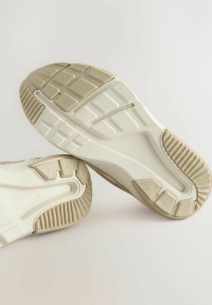 Scarpe sportive bianche con suole testurizzate e suole in gomma a motivo. Le caratteristiche includono una forma curva e accenti di un beige chiaro.