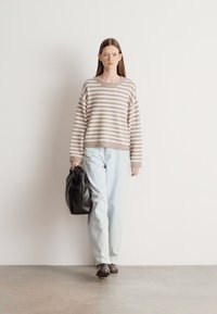 Triibuline kudum, beeži ja kreemika tooniga, koos helesiniste lahtiste teksade ja musta nahast kotiga. Sujuv tekstuur, vaba lõige.