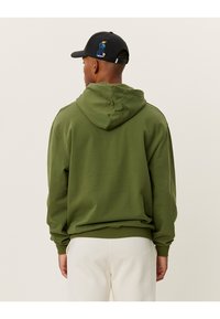 Felpa verde oliva con cappuccio regolabile e polsini a costine, caratterizzata da un tessuto testurizzato e un design ricamato colorato sulla parte superiore.